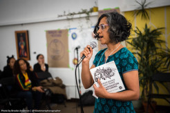 Pictured here is MG collective member Michelle Mascarenhas-Swan speaking into a microphone while holding a copy of the MG Just Transition Zine